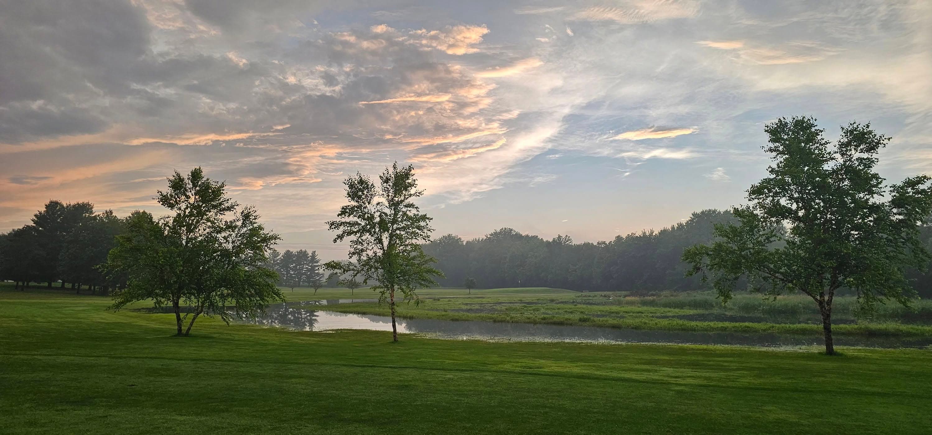 Pond and tree line at La Porte City Golf Club at dusk.