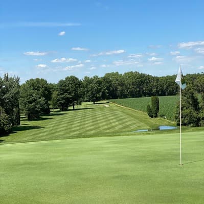 Approach view of a green at La Porte City Golf Club with the flag and trees behind.